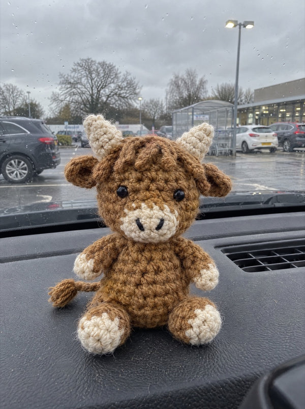 Crocheted Highland cow on a car dashboard